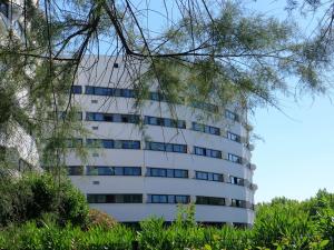 een hoog wit gebouw met bomen ervoor bij Studio Ulysse Plage-12 by Interhome in La Grande-Motte