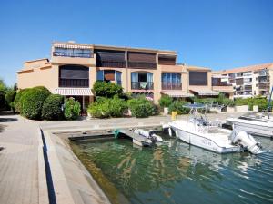 a boat docked in a marina in front of a building at Apartment Marina 2-2 by Interhome in Saint-Cyprien-Plage