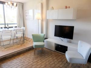 een woonkamer met een televisie en een tafel en stoelen bij Apartment Les Catalanes du Golf by Interhome in Saint-Cyprien