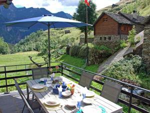 een tafel met een parasol op een balkon bij Chalet Rustico Orino by Interhome in Alpe di Scieru