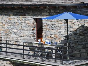 a table with a blue umbrella and two chairs at Chalet Rustico Orino by Interhome in Alpe di Scieru