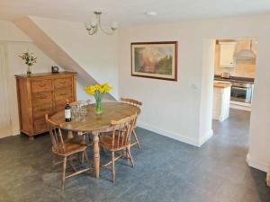 a dining room with a table and chairs and a kitchen at Cross Beck Cottage in Grinton