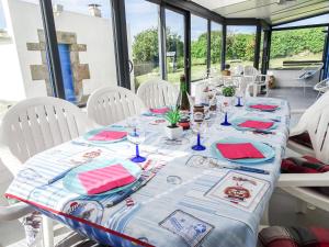 a table with white chairs and a blue and white table cloth at Holiday Home Kerludu by Interhome in Kerloch