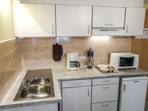 uma cozinha com armários brancos, um lavatório e um micro-ondas em Apartment Résidence jaune et rose-2 by Interhome em Marckolsheim