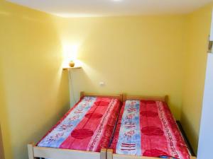 um pequeno quarto com uma cama com um edredão vermelho em Apartment Résidence jaune et rose-2 by Interhome em Marckolsheim