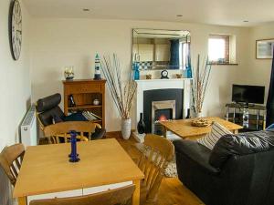 a living room with a couch and tables and a fireplace at Crud yr Awel in Y Felinheli