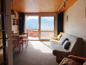 a living room with a couch and a large window at Apartment Le Super Venosc by Interhome in Les Deux Alpes