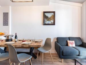 a dining room with a table and a blue couch at Apartment Le Curling A-9 by Interhome in Tignes