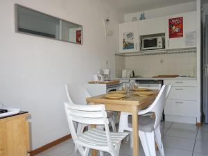 a kitchen with a wooden table and white chairs at Apartment Les Aigues Marines-36 by Interhome in La Madrague