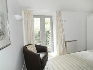 um quarto com uma cama e uma cadeira ao lado de uma janela em Holemire Barn em Cockermouth