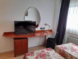Habitación con escritorio, espejo y cama. en Hotel Donizetti, en Lallio