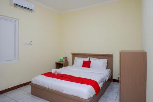 a bedroom with a large bed with a red blanket at RedDoorz near Tugu Muda Semarang in Kalibanteng-lor