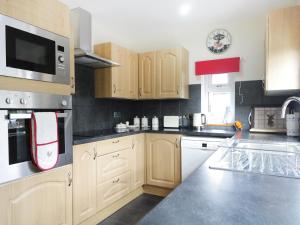 a kitchen with wooden cabinets and stainless steel appliances at St Aethans in Inveran