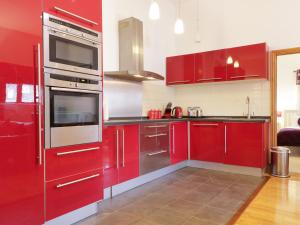 a red kitchen with stainless steel appliances and red cabinets at Keswick Loft in Keswick