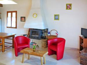 ein Wohnzimmer mit 2 roten Stühlen und einem Kamin in der Unterkunft Holiday Home Le Chêne by Interhome in Blanquefort-sur-Briolance