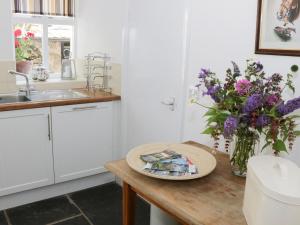 eine Küche mit einem Tisch mit einer Blumenvase in der Unterkunft Coachmans Cottage in Levens + 8 Fotos
