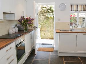 LevensにあるCoachmans Cottageの白いキャビネットと花瓶付きのキッチン