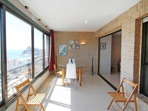 Habitación con mesa, sillas y ventanas grandes. en Apartment Coblanca-1 by Interhome, en Benidorm