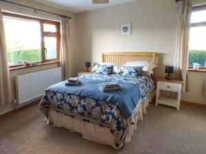 a bedroom with a large bed with a blue comforter at Tynddol Bungalow in Llanbadarn-fynydd