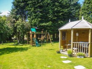 a backyard with a playground and a swing at Tynddol Bungalow in Llanbadarn-fynydd