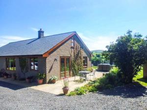 a small brick house with a patio and a table at Tynddol Bungalow in Llanbadarn-fynydd