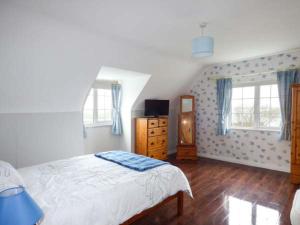 a bedroom with a bed and a dresser and two windows at No 1 Apt, Brandy Harbour Cottage in Kilcolgan