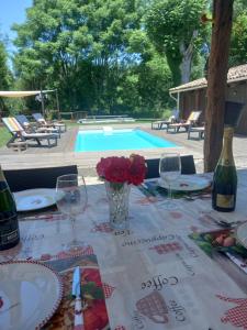 a table with wine glasses and flowers and a pool at Gite Rural Charente Maritime in Bran
