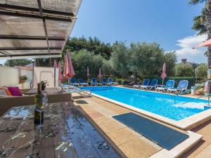 a swimming pool with chairs and a bottle of wine at Apartment Nena - PRC426 by Interhome in Nova Vas
