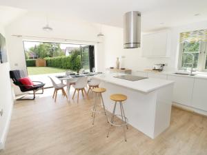 a kitchen with white counters and stools and a table at Appletree Cottage in Bishampton