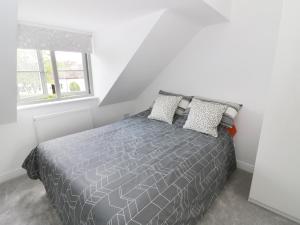 a bedroom with a gray bed with two pillows at Appletree Cottage in Bishampton