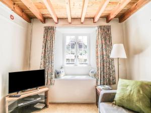 a living room with a tv and a window at Old Hammetts in Woolfardisworthy