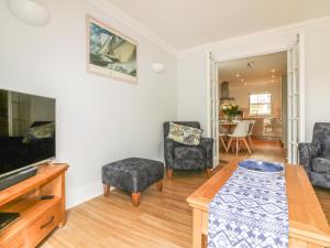 uma sala de estar com uma televisão e duas cadeiras e uma mesa em 7 The Retreat em Paignton