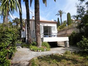 カンヌにあるHoliday Home Villa Esmeralda by Interhomeの椰子の木とポーチのある家