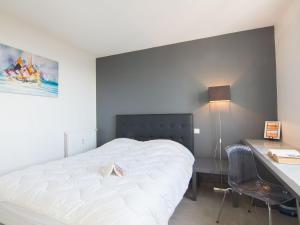 a bedroom with a white bed and a desk with a lamp at Apartment Le Parc Cordier-3 by Interhome in Trouville-sur-Mer