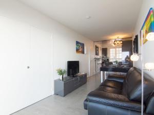 a living room with a leather couch and a television at Apartment Le Parc Cordier-3 by Interhome in Trouville-sur-Mer