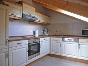 La cuisine est équipée de placards blancs et d'un four avec plaques de cuisson. dans l'établissement Apartment Bibelöd-5 by Interhome, à Ruhpolding