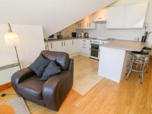 a living room with a leather chair and a kitchen at Shorefields One in Morecambe