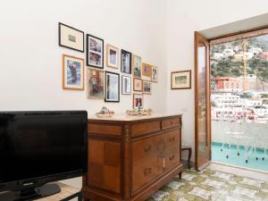 een woonkamer met een tv, een dressoir en een raam bij Apartment A'Scalinatella by Interhome in Positano