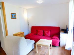 a living room with a red couch and a table at Studio L'Enclave I et J-28 by Interhome in Les Contamines-Montjoie