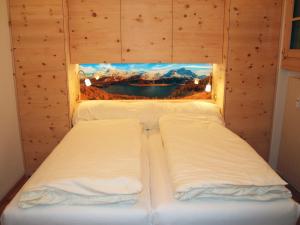 two beds in a room with a picture on the wall at Apartment Chesa Alvetern 5 by Interhome in Sils Maria