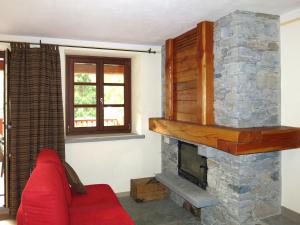 a living room with a stone fireplace and a red couch at Apartment La Borgata - SMY726 by Interhome in Sampeyre