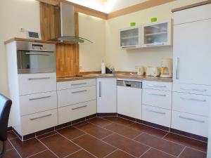 a kitchen with white cabinets and a brown tile floor at Holiday Home Edelmann by Interhome in Schnett