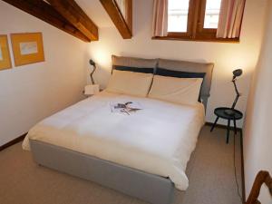 a bedroom with a large white bed with two lamps at Apartment Chesa Prasüra 10 by Interhome in Sils Maria