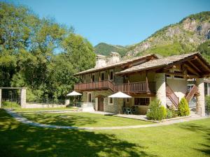 a large house with a green yard and a mountain at Apartment Casa del Ponte - SMY622 by Interhome in Sampeyre