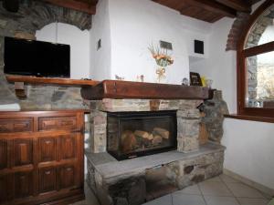 a living room with a stone fireplace with a flat screen tv at Holiday Home Caa de Sass by Interhome in Castelveccana