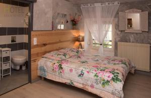 a bedroom with a bed and a toilet in it at Hôtel Les Remparts in Nozeroy