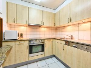uma cozinha com armários de madeira e um micro-ondas em Apartment Ringstrasse - Utoring-42 by Interhome em Leukerbad