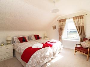 a bedroom with a bed with red pillows and a window at Meadowside Farm in Coupar Angus