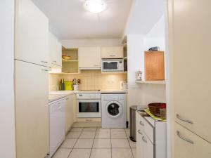 eine kleine Küche mit weißen Schränken und einer Waschmaschine und einem Trockner in der Unterkunft Apartment Le Magellan-1 by Interhome in Saint-Raphaël
