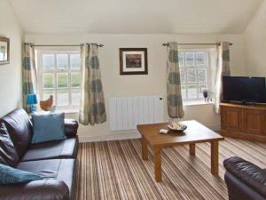 a living room with a couch and a coffee table at Curlew Cottage in Warslow